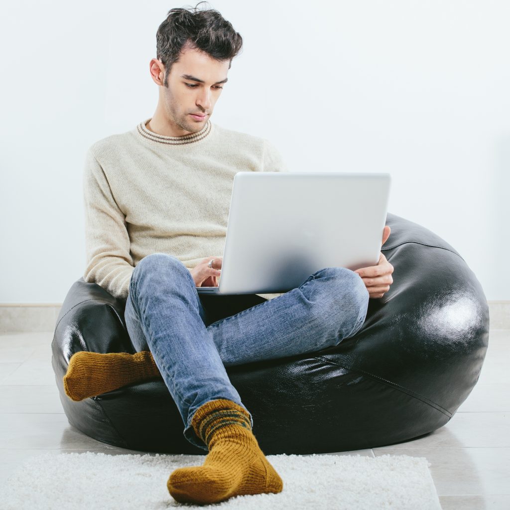 Fashionable man in winter knitted clothes with laptop